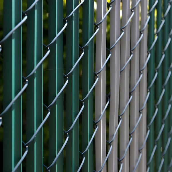 Detailaufnahme eines Zauns mit vertikalen Lamellen und Maschendraht