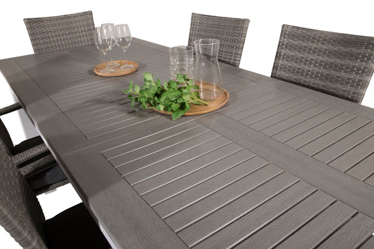 Detailansicht eines Esstisches mit Flechtstühlen, Gläsern und Dekoration