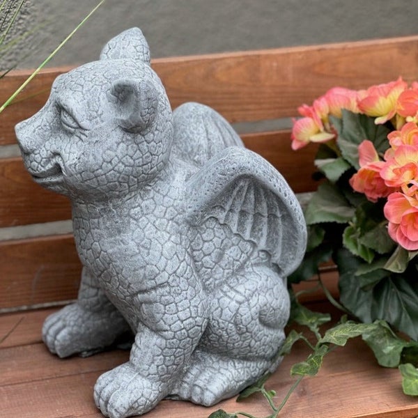 Dekorative Gartenfigur Drache aus Steinguss für den Außenbereich auf einer Holzbank.