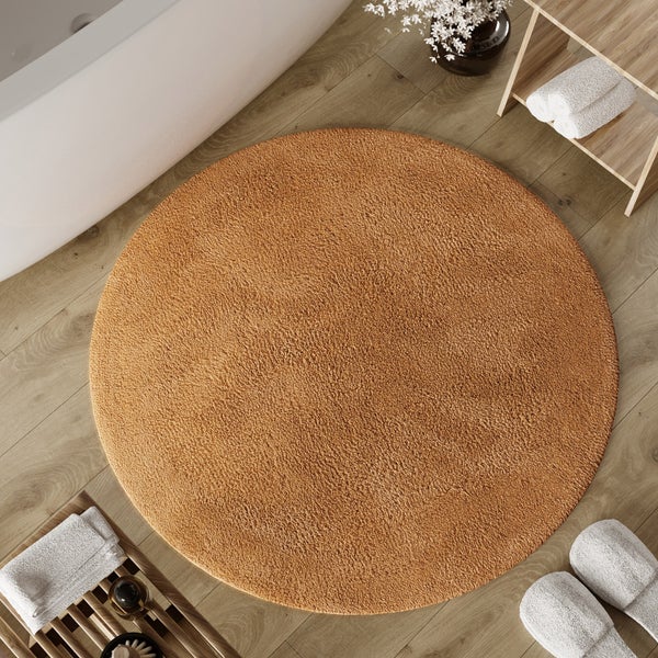 Runder Badteppich in einem Badezimmer mit Holzboden, Badewanne und Badmöbeln aus Holz.