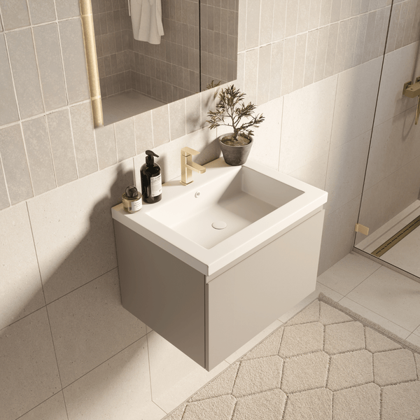 Moderner wandhängender Waschtischunterschrank in Beige mit weißem Keramikwaschbecken und goldener Armatur in einem hell gefliesten Badezimmer.