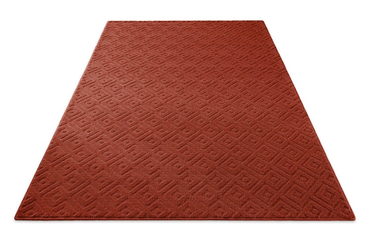 Rechteckiger Teppich in Terracotta mit geometrischem Rautenmuster in perspektivischer Ansicht.