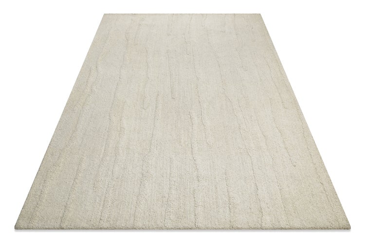 Nahaufnahme der strukturierten Oberfläche und der Kante eines Hochflor-Teppichs mit horizontalen Linien.