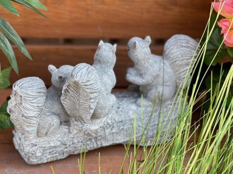Gartenfigur aus Kunststein in Form von drei Eichhörnchen auf einem Baumstamm als Dekoration für den Außenbereich