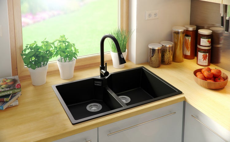 Schwarze Doppelspüle mit Armatur in einer hellen Küche.