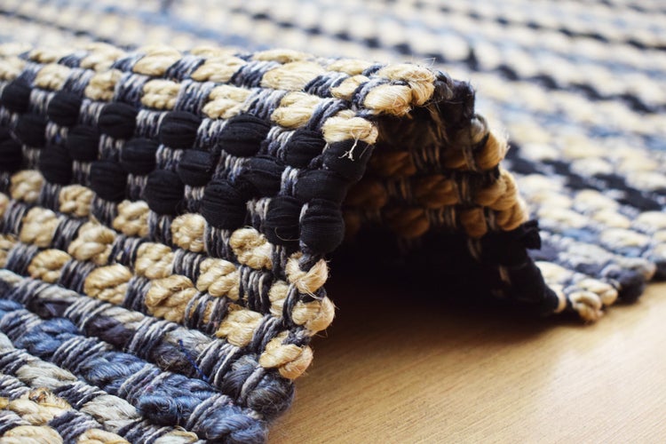 Grob gewebter Teppich mit Flechtmuster in Beige und Dunkelblau, Detailansicht der Textur.