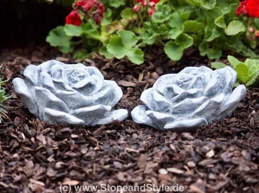 Zwei dekorative Rosenblüten als Gartenfigur aus Stein im Beet
