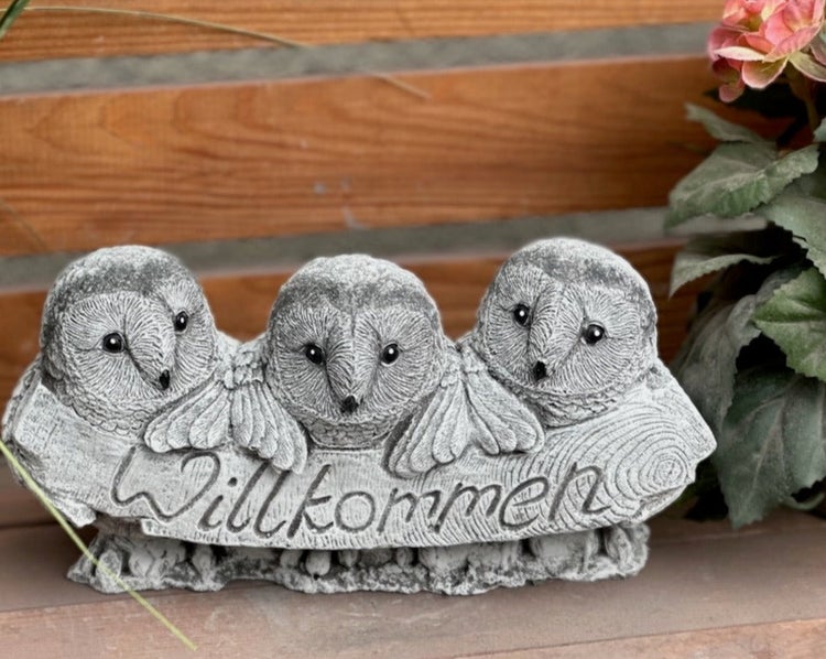 Dekorative Gartenfigur aus Steinguss mit drei Eulen und einem Schild mit der Aufschrift Willkommen.