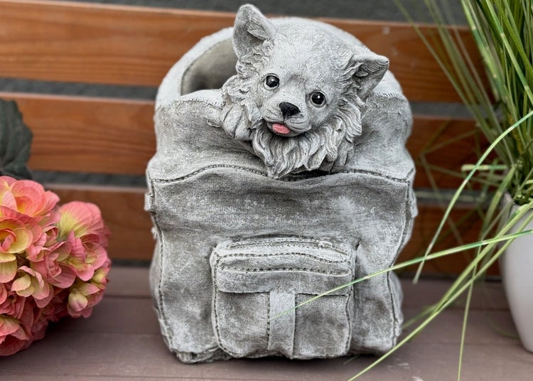 Pflanztopf als Gartenfigur in Form eines Hundes im Rucksack aus Steinguss.