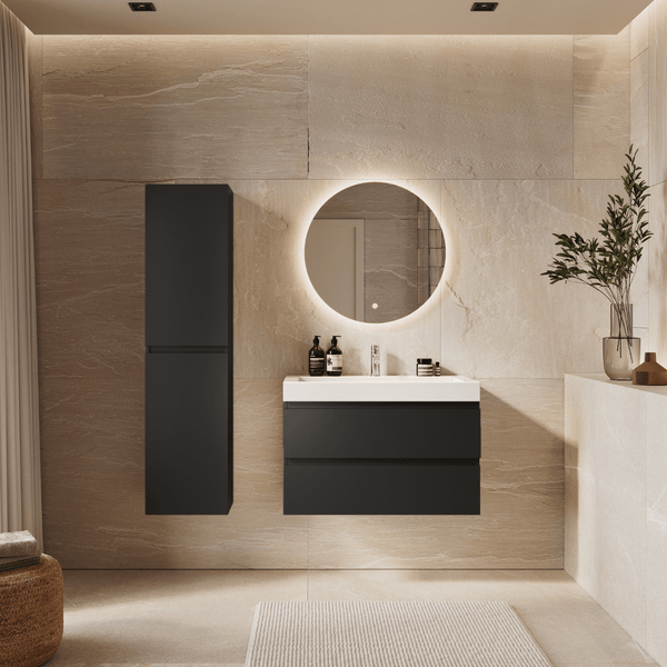Modernes Badezimmer mit dunkelgrauem Waschtischunterschrank, weißem Waschbecken, Hochschrank und rundem beleuchtetem Spiegel vor Steinwand.