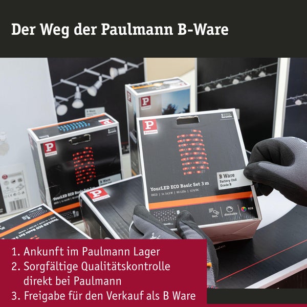 Hände in Arbeitshandschuhen halten eine Produktverpackung von Paulmann LED Streifen gekennzeichnet als B Ware in einem Lager