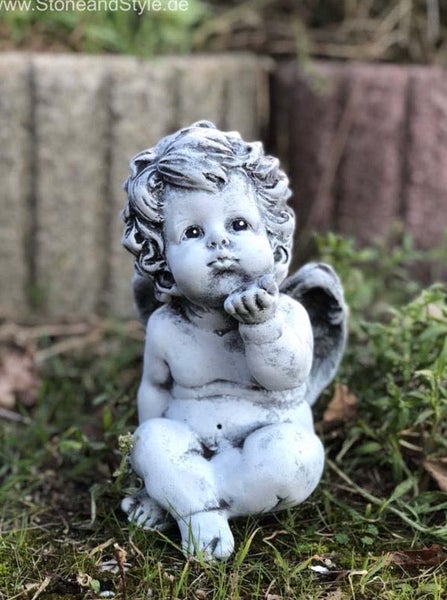 Steinfigur Engel mit lockigem Haar, der einen Kuss zuwirft, als Dekoration für den Garten aus witterungsbeständigem Material.
