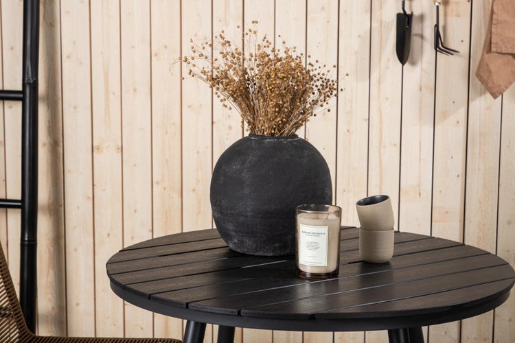 Dekorative Szene mit einem runden Tisch, einer Vase mit Trockenblumen, einer Kerze und zwei Bechern