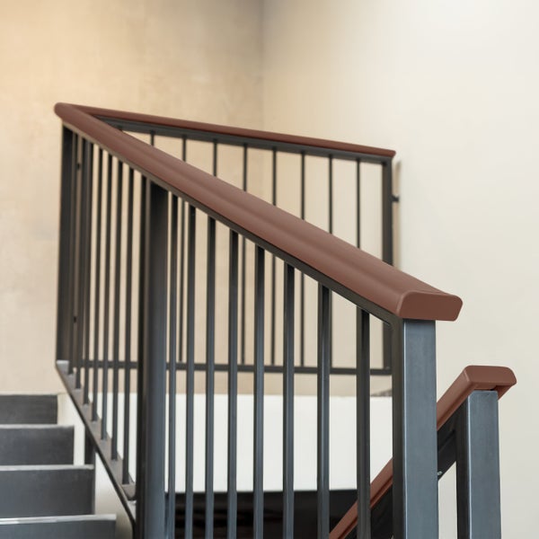 Modernes Treppengeländer mit dunklen Metallstäben und braunem Holzhandlauf an einer hellen Innentreppe.