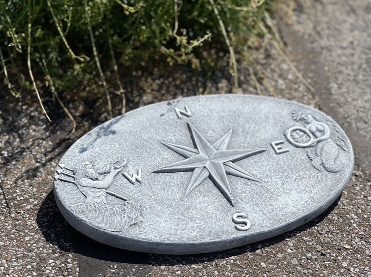 Ovale Trittplatte aus Stein mit Kompassrose und maritimen Motiven als Gartenweg Dekoration