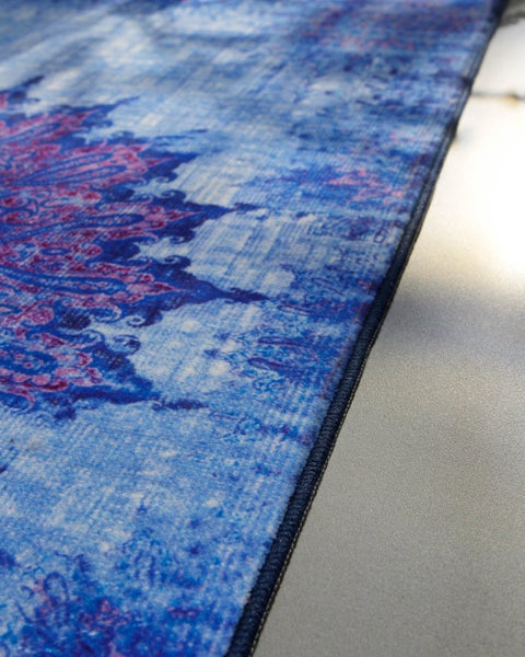 Detailaufnahme eines blau-pinken Teppichs mit orientalischem Mandala-Muster im Vintage-Stil und dunkler Kettelkante.