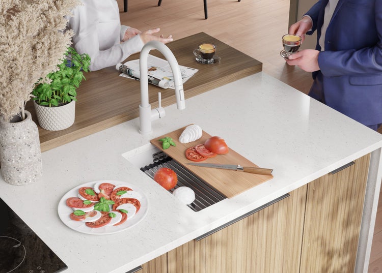 Helle Küche mit Spüle, Armatur, Schneidebrett mit Tomaten und Mozzarella für die Zubereitung von Caprese.