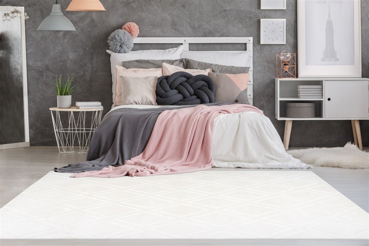 Nahaufnahme eines weißen, weichen Teppichs mit geometrischem Hoch-Tief-Muster aus Mikrofaser.