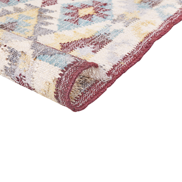 Gewebter Kelim-Teppich mit geometrischem Muster und Fransen, eine umgeschlagene Ecke zeigt die Struktur des Gewebes.