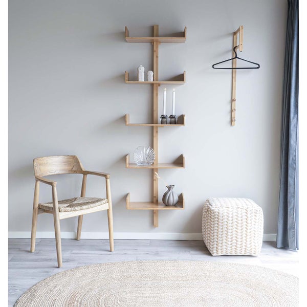 Wandregal aus Bambus mit 5 Ebenen in einem hellen Wohnzimmer mit Holzstuhl, Hocker und rundem Teppich.