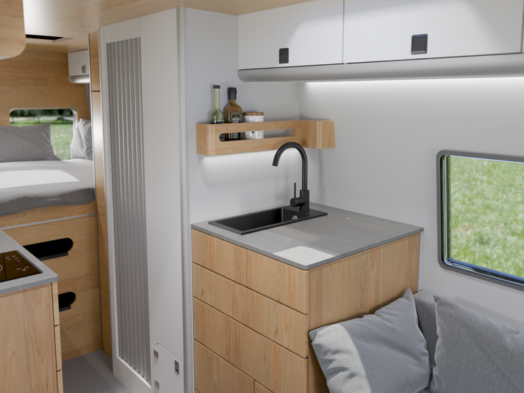 Moderne Wohnmobil-Küchenzeile mit Holzschrank, schwarzer Armatur und Spüle, hell und organisiert gestaltet, mit Blick auf den Schlafbereich.