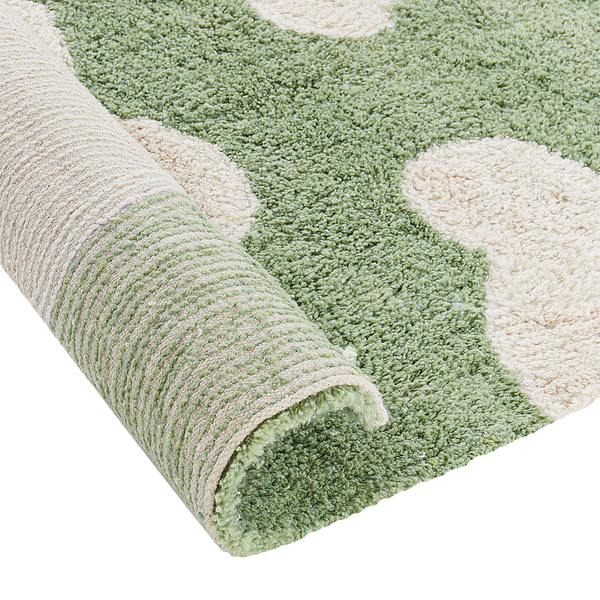 Weicher Hochflor-Teppich mit floralem Muster in Grün und Beige, Detailaufnahme der weichen Struktur und der Unterseite.