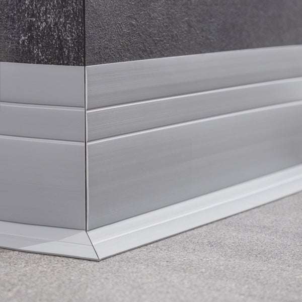 Fußleiste aus Aluminium an einer Innenecke montiert mit strukturierter Wand und Bodenbelag