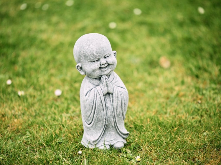 Steinfigur kleiner lachender Buddha in Gebetshaltung als Gartendekoration