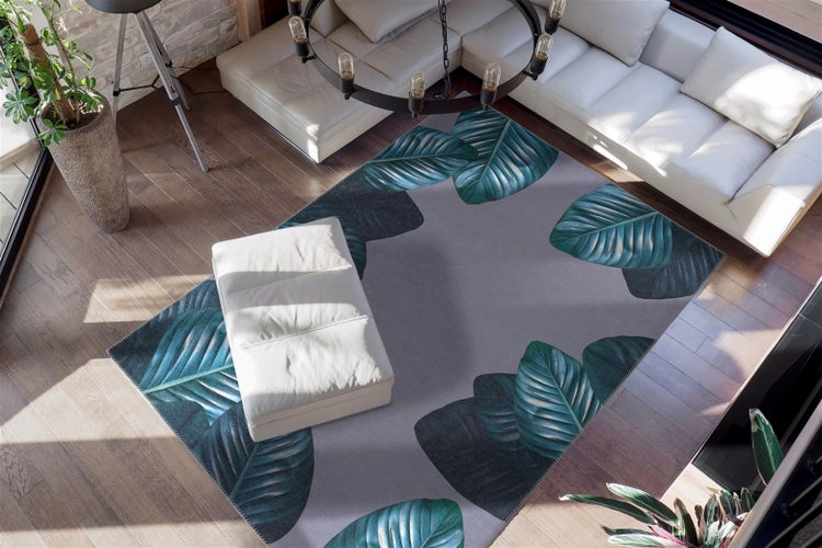 Grauer Teppich mit grünem Blattmuster in einem hellen Wohnzimmer mit weißem Ecksofa und Holzboden in der Draufsicht.