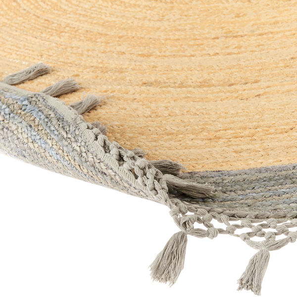 Nahaufnahme eines runden gewebten Teppichs mit Quasten und grauem Rand.