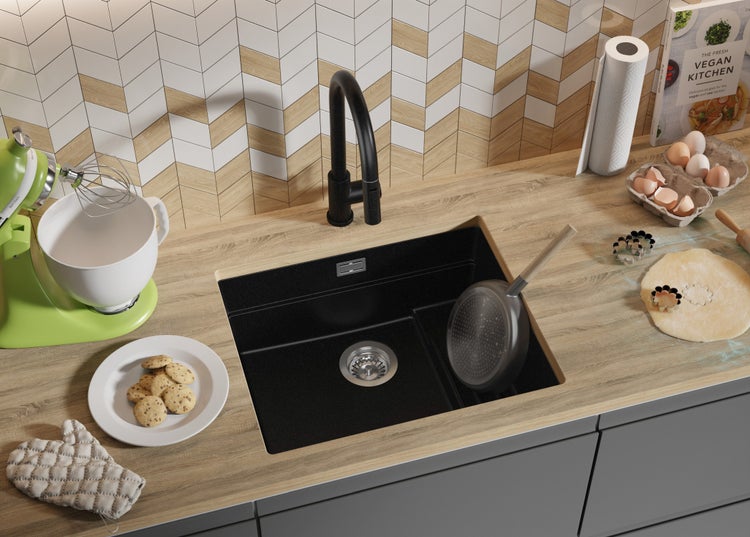 Küchenszene mit Spüle, Armatur, Küchenmaschine, Kochbuch, Eiern und Keksen auf einer Arbeitsplatte