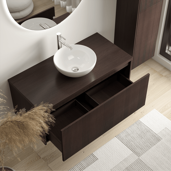 Moderner Waschtischunterschrank in dunkler Holzoptik mit geriffelter Front, Aufsatzwaschbecken aus Keramik und geöffneter Schublade.