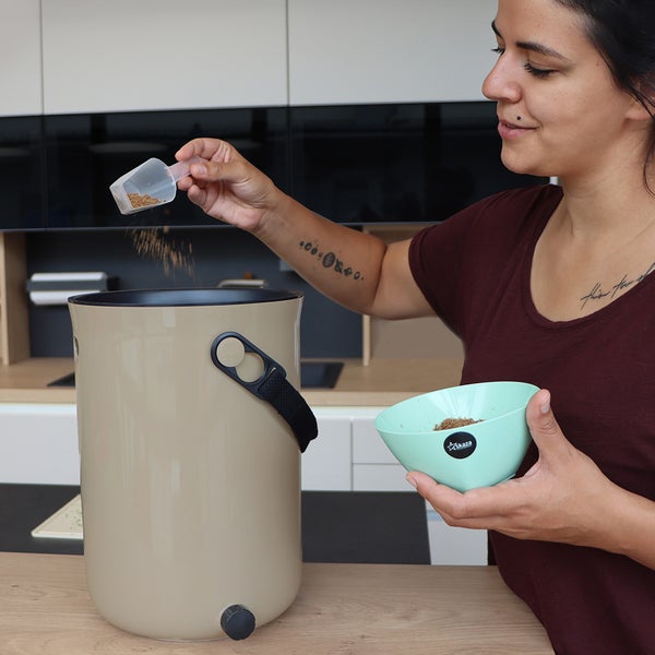 Frau befüllt einen Bokashi-Eimer mit Küchenabfällen für die Kompostierung.