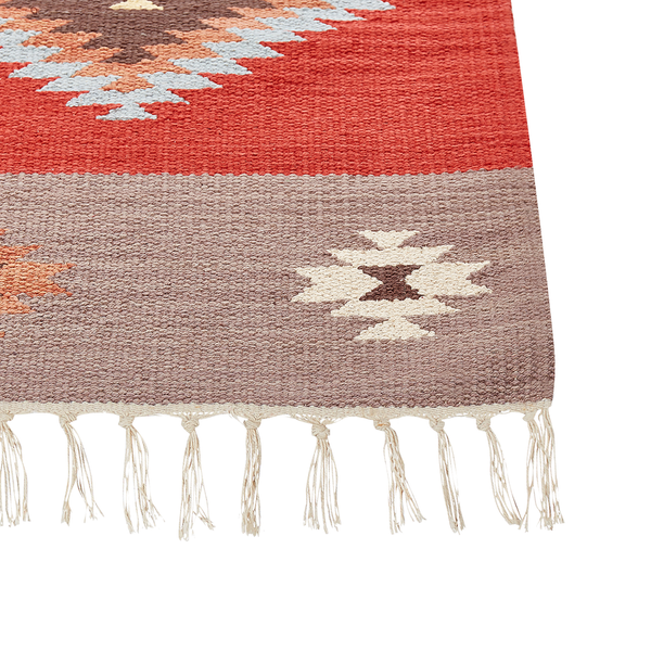 Gewebter Teppich in Terracotta mit Ethno-Muster und Fransen.