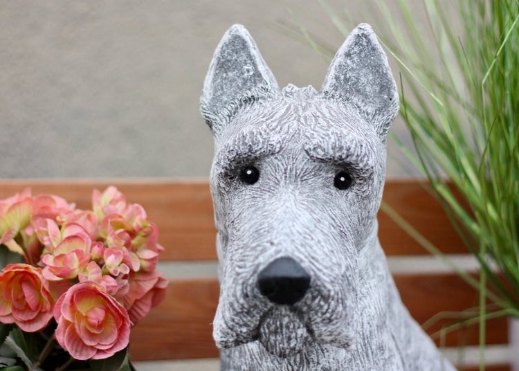 Gartenfigur Hund in Steinoptik neben Blumen vor einer Holzbank