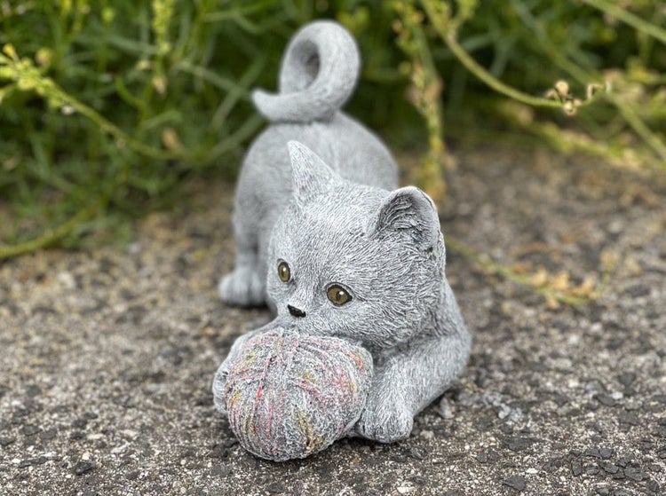 Steinfigur Kätzchen spielend mit einem Wollknäuel als Dekoration für den Garten
