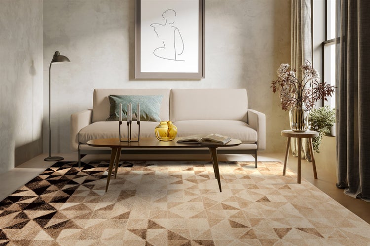 Modernes Wohnzimmer mit hellem Sofa und einem Teppich mit geometrischem Dreiecksmuster in Beige- und Brauntönen.