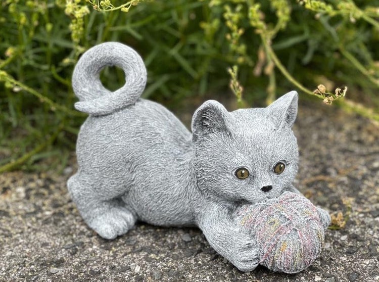Dekorative Gartenfigur in Form eines Kätzchens, das mit einem Wollknäuel spielt, aus witterungsbeständigem Material für den Außenbereich.