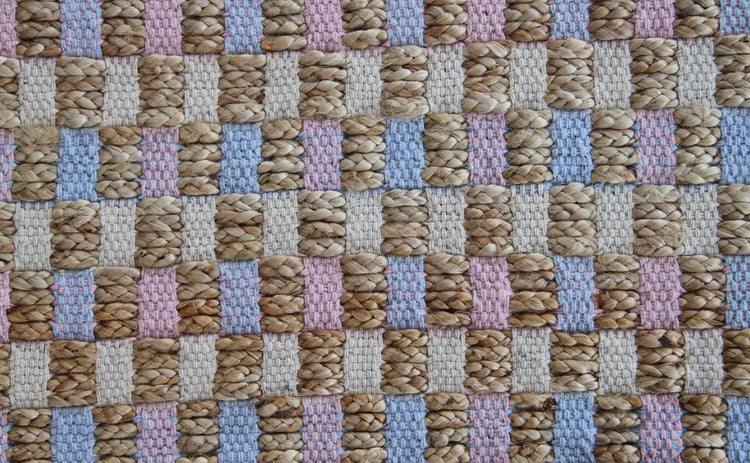 Detailansicht eines gewebten Teppichs mit Karomuster aus Jute und Textil.