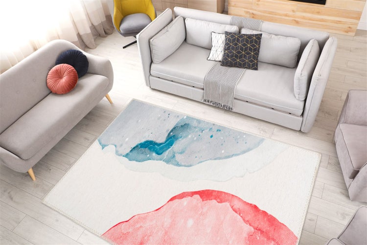 Moderner Wohnraum mit hellem Teppich im Aquarell-Design in Blau- und Rosatönen, grauen Sofas und hellem Holzboden.