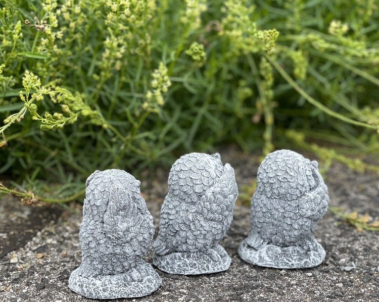 Drei Eulenfiguren aus Steinguss in Gartenlandschaft