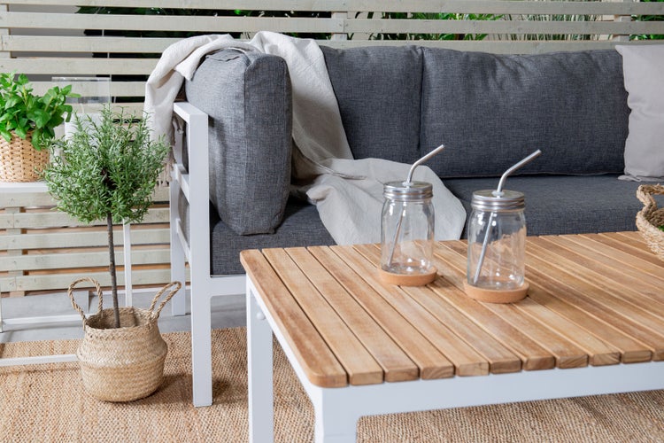 Außensitzbereich mit grauem Sofa, Holztisch und Pflanzen