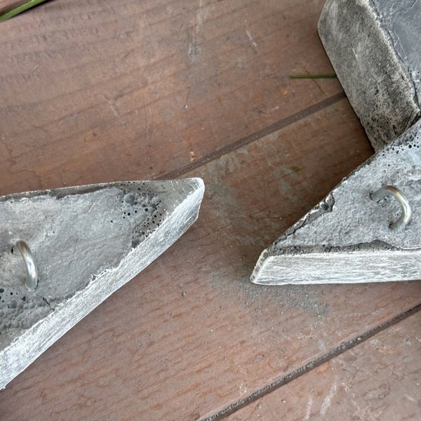 Zwei dekorative Betonelemente in Sternform mit integrierten Metallösen zur Befestigung