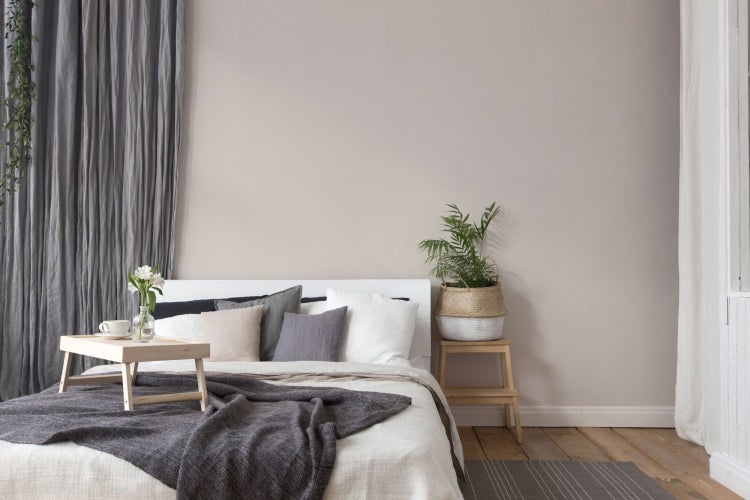 Nahaufnahme eines Tisches mit Pflanze, Deko-Häusern und Bilderrahmen vor einer Tapete mit Punktmuster