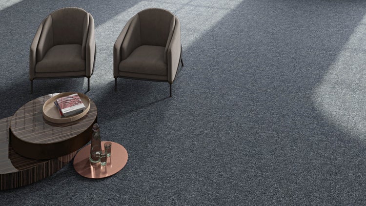 Modernes Wohnzimmer mit grauem Teppichboden, zwei taupefarbenen Sesseln und einem gestuften Couchtisch aus dunklem Holz in heller Atmosphäre.