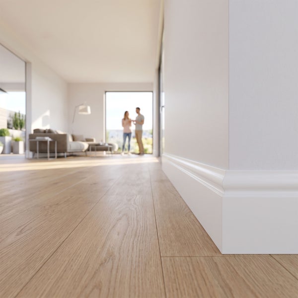 Weiße profilierte Sockelleiste auf hellem Holzboden in einem modernen hellen Wohnzimmer mit unscharfem Hintergrund.