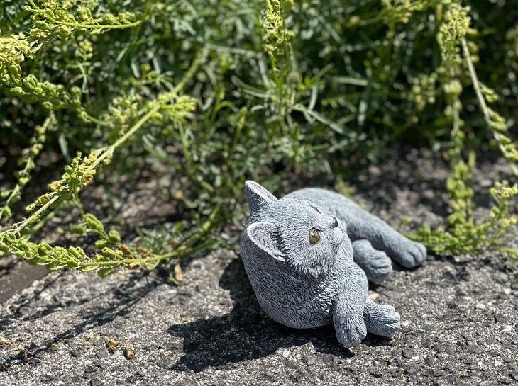 Dekorative Gartenfigur in Form einer liegenden Katze aus wetterfestem Kunststein für den Außenbereich.
