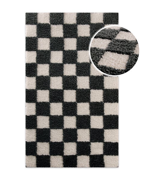 Rechteckiger schwarz-weißer Teppich mit Schachbrettmuster und weicher Hochflor-Struktur.