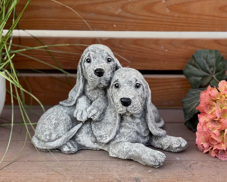 Gartenfigur aus Steinguss: Zwei niedliche Hundewelpen mit Schlappohren, liegend.