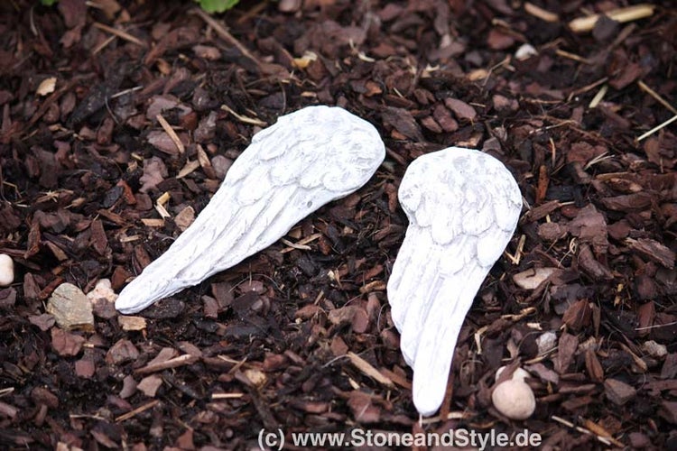 Zwei Engelsflügel aus Steinguss zur Gartendekoration auf Rindenmulch